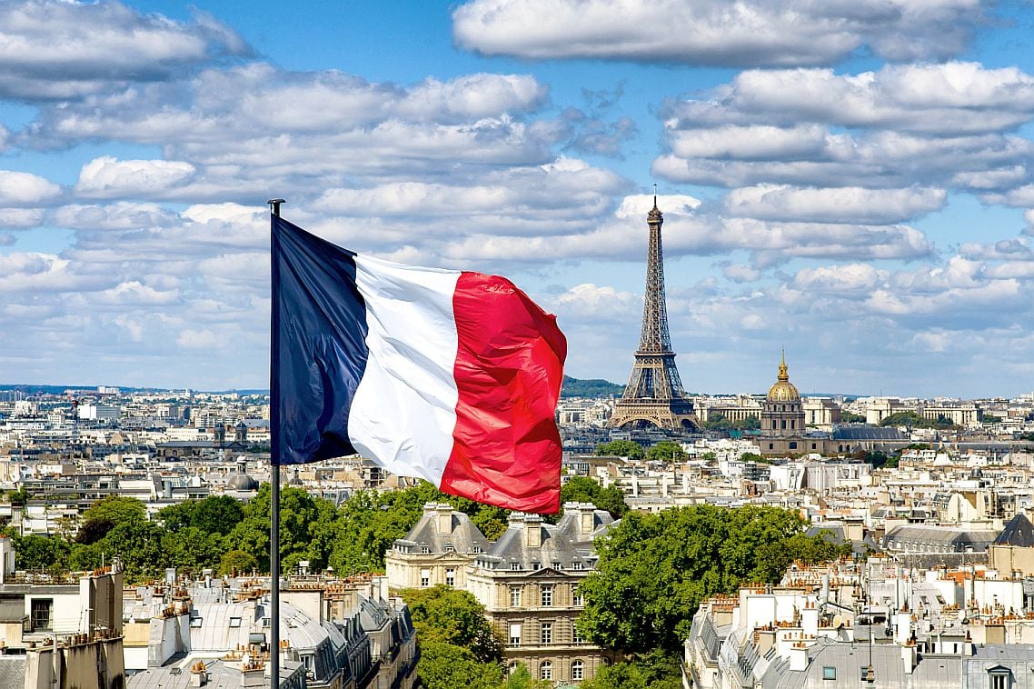 The French flag flies on a building with the Eiffel Tower in the background