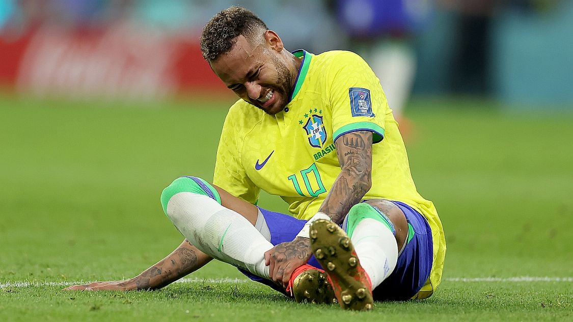 Soccer star Neymar holds his ankle following an injury during a game